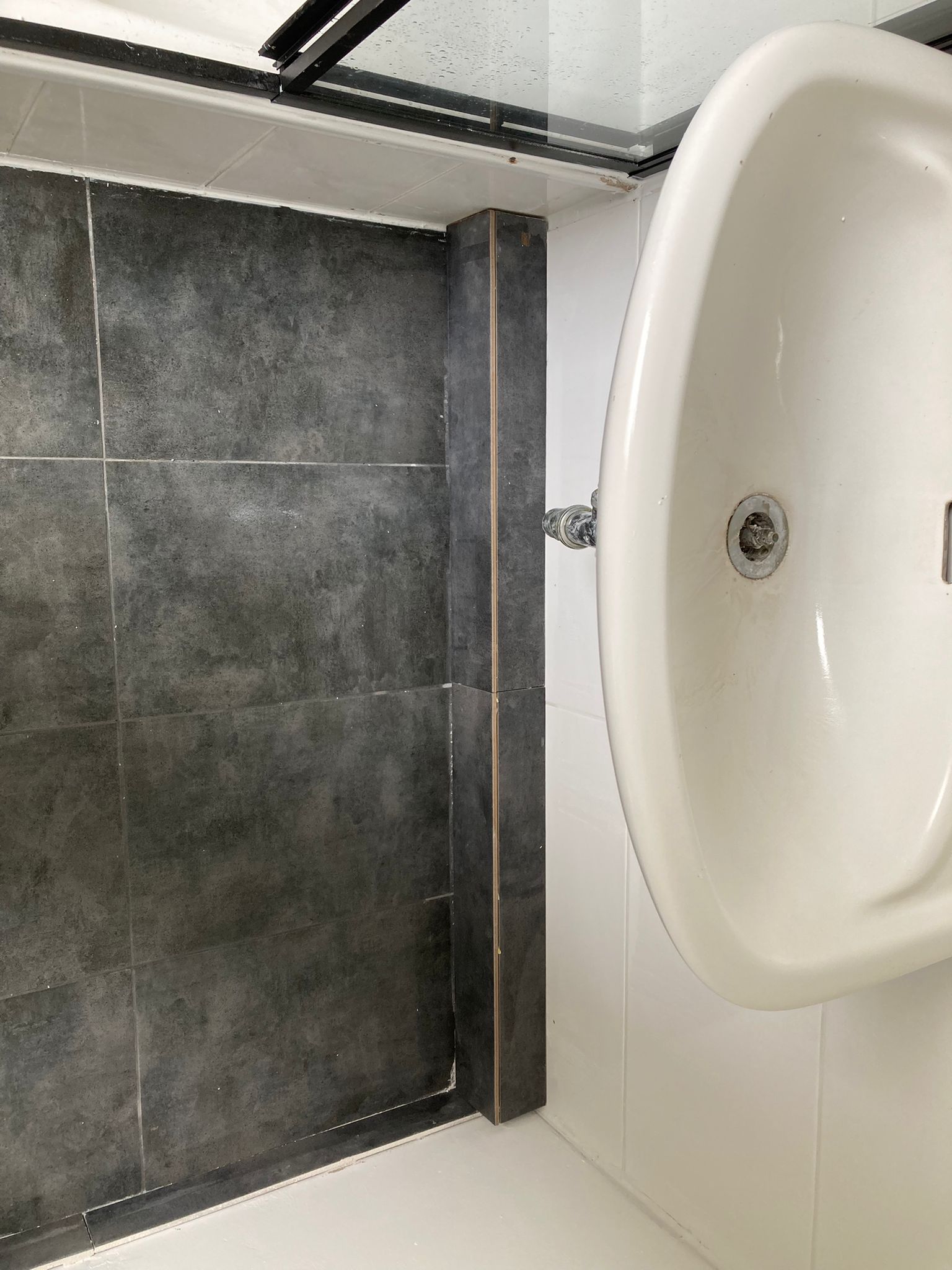 Fliesenarbeiten mit gefliester Rohrverkleidung unter einem Waschbecken